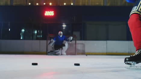 Close-up-of-a-hockey-puck-in-slow-motion-and-a-putter-of-several-pucks-in-turn-and-a-goalkeeper-in-the-background